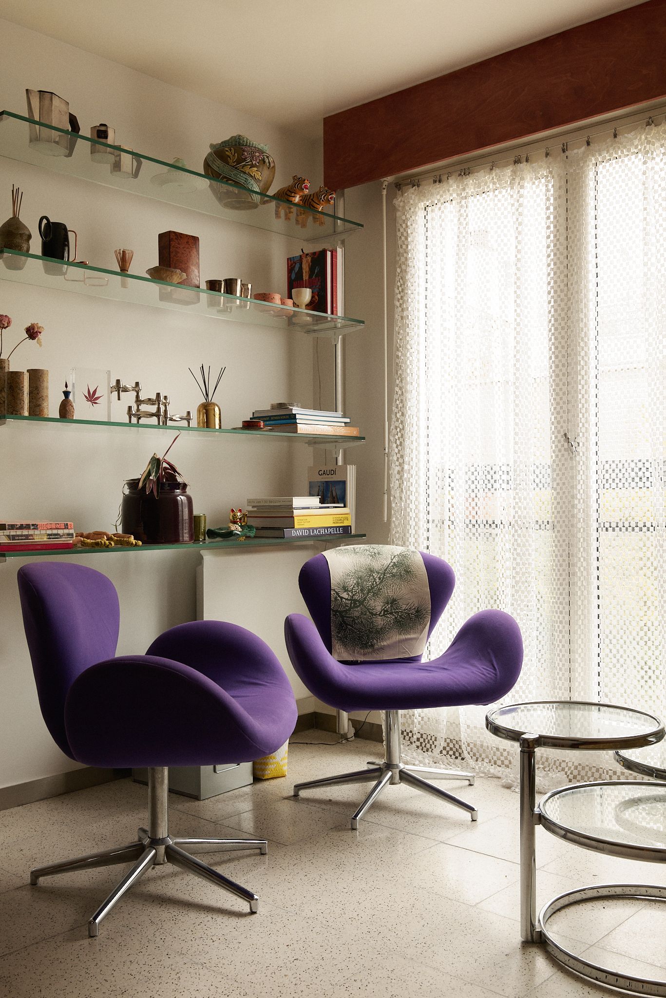 Poltrone viola mensole con oggetti finestre con tende.