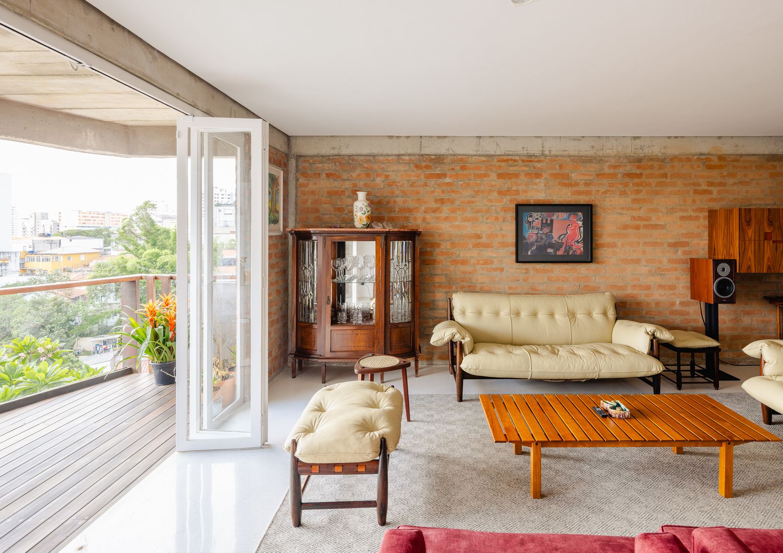 sofa color beige con mesa delante de madera ventana abierta y pared de ladrillo