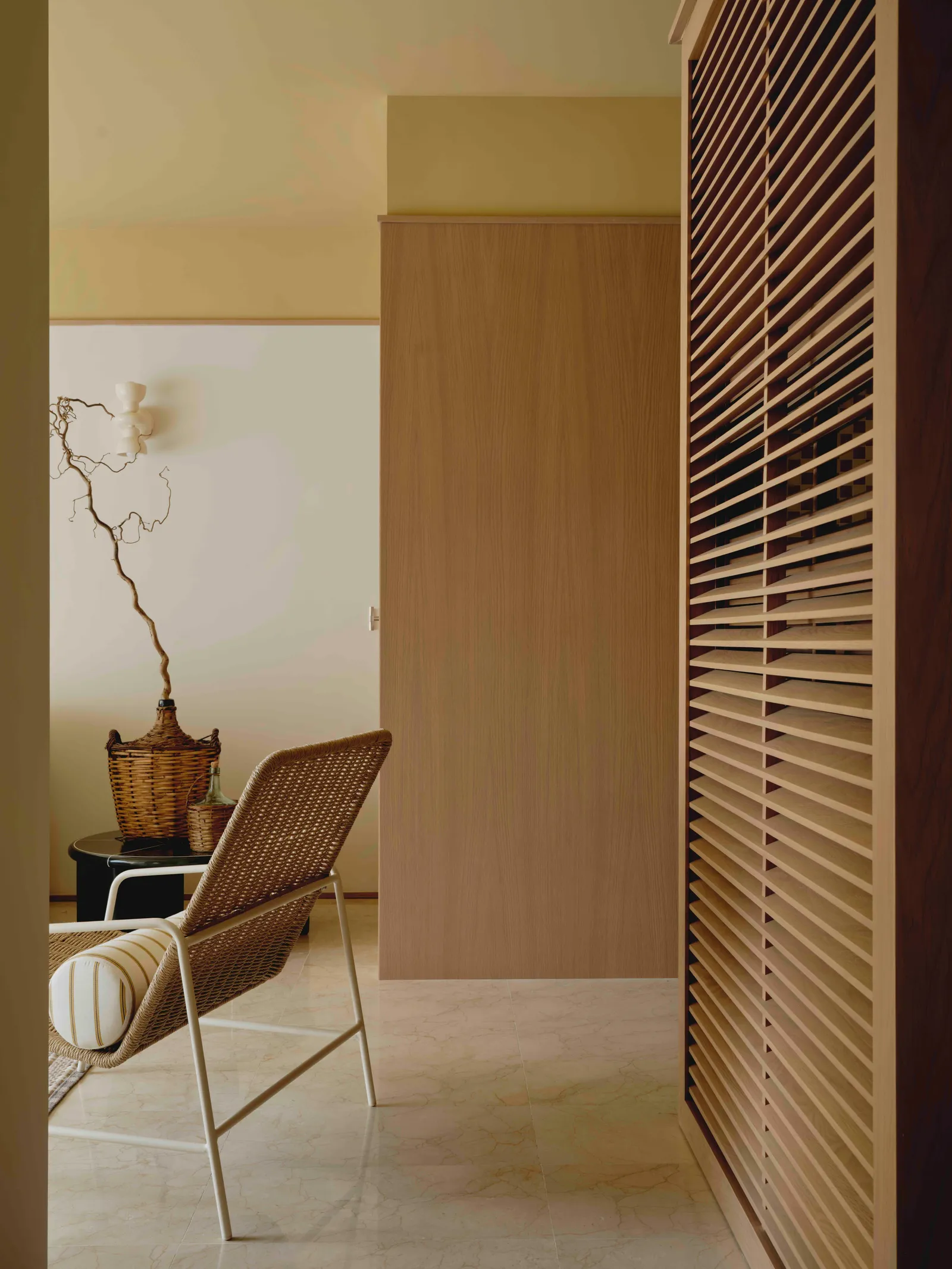 detalle del salón con butaca de mimbre y arreglo floral detrs en cesta de mimbre